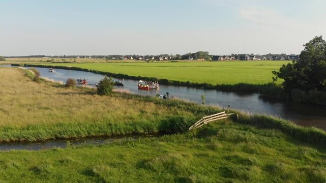 Aerial view of serene river with boats and lush green fields, Arum, Netherlands.