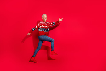 Full body photo of attractive senior woman walk excited empty space dressed theme party sweater isolated on red color background