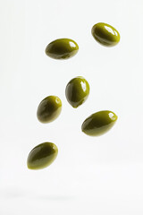 Green olives falling down on white background