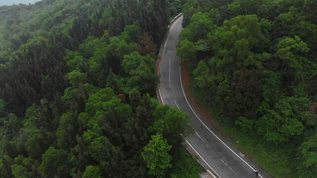 Aerial view of the scenic curve of the famous Hai Van Pass road surrounded by lush greenery and mountains, Da Nang, Vietnam.