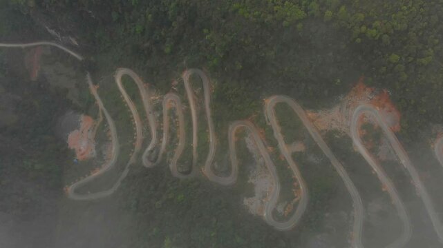 Aerial view of winding mountain pass with hairpin curves and clouds, Khau Coc Cha, Cao Bang, Vietnam.