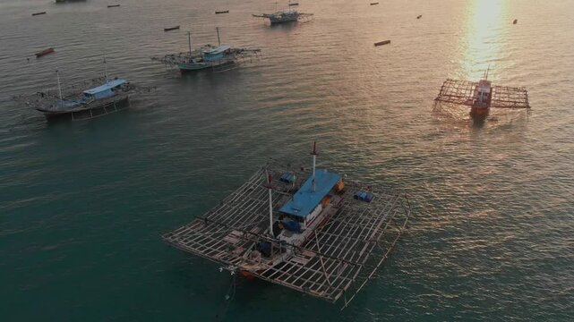 Aerial view of tranquil fishing village with boats on calm sea at sunset, Tanjung Binga, Indonesia.