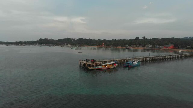 Aerial view of a beautiful fishing village with a pier and boats at sunset over the sea, Tanjung Binga, Indonesia.