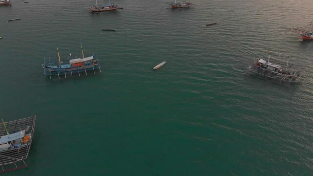 Aerial view of serene fishing village at sunset with boats on calm sea, Tanjung Binga, Indonesia.