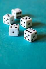 Five dice on a teal background with side lighting.