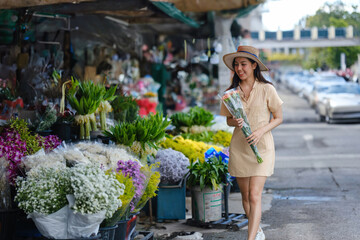 A woman is walking down a street with a bouquet of flowers in her hand
