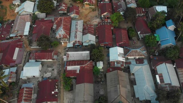 Aerial view of vibrant village with charming houses and lush greenery during sunset, Tanjung Binga, Indonesia.