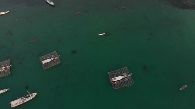 Aerial view of fishing boats on a tranquil sea at sunset near a traditional village, Tanjung Binga, Indonesia.