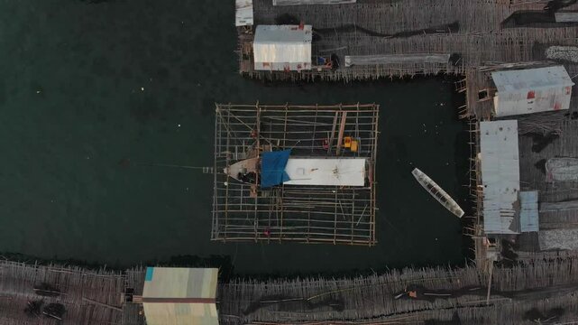 Aerial view of a tranquil fishing village with wooden structures and boats at sunset, Tanjung Binga, Indonesia.