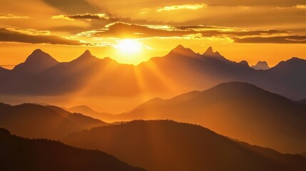 Fototapeta premium Sun setting behind a mountain range, casting golden light across the landscape.