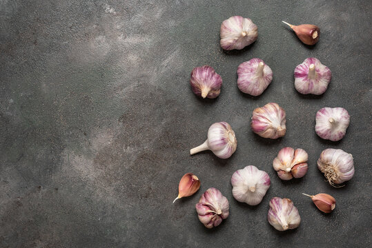 Fresh garlic on dark grunge background, top view, flat lay, copy space.