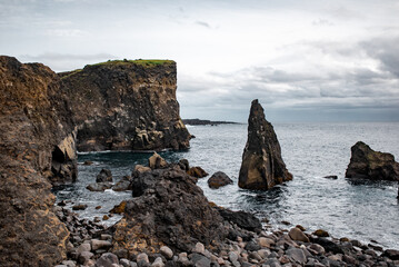 Rocky cliffs and stormy sea under a cloudy sky.