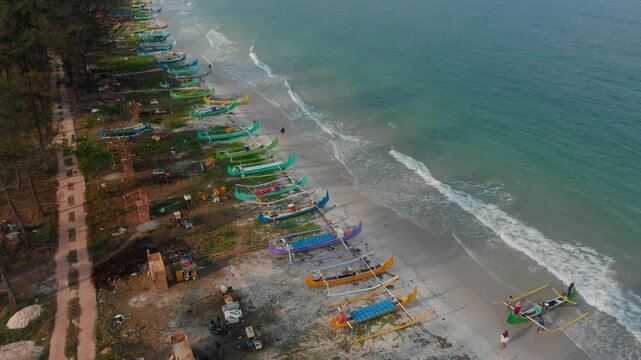 Aerial view of serene beach with traditional fishing boats along the coastline, Manggar, Indonesia.
