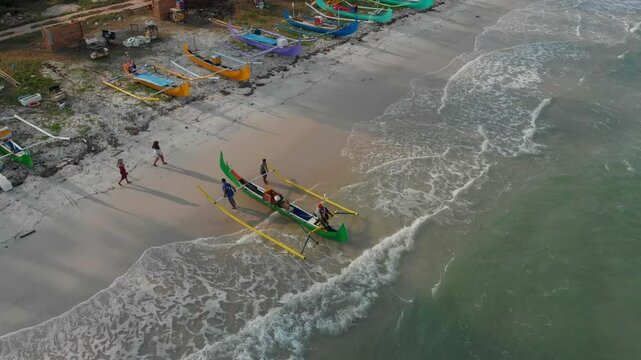 Aerial view of traditional fishing boats on a beautiful sandy beach by the sea, Manggar, Indonesia.
