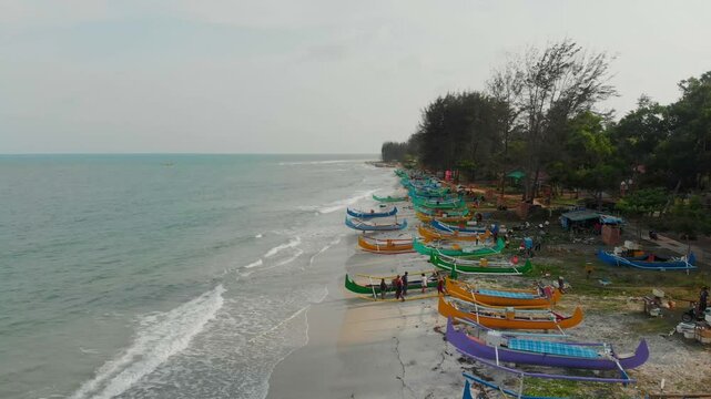 Aerial view of serene serdang beach with traditional fishing boats along the tranquil coastline, Manggar, Indonesia.