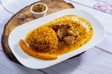 A mouthwatering dish of Seco de chivo chancho featuring a rich and savory sauce, served with tender chunks of goat, pork, and beef. Accompanied by a generous portion of moros de lenteja (lentil rice)