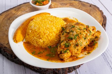 A vibrant, traditional Ecuadorian dish, Seco de Pollo, served with flavorful yellow rice and fried...