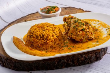 A vibrant, traditional Ecuadorian dish, Seco de Pollo, served with flavorful yellow rice and fried...