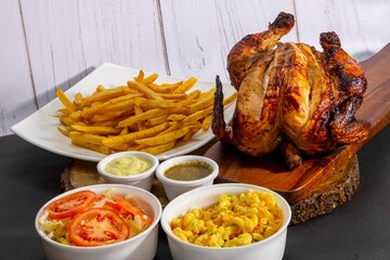 Deliciously charred and smoky Pollo a la Brasa (grilled chicken) served whole and in pieces, accompanied by crispy fries, fresh salad, and a flavorful dipping sauce. A classic Latin American dish, coo