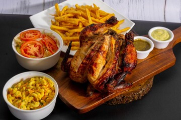Deliciously charred and smoky Pollo a la Brasa (grilled chicken) served whole and in pieces, accompanied by crispy fries, fresh salad, and a flavorful dipping sauce. A classic Latin American dish, coo
