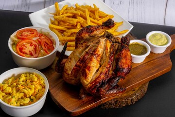 Deliciously charred and smoky Pollo a la Brasa (grilled chicken) served whole and in pieces, accompanied by crispy fries, fresh salad, and a flavorful dipping sauce. A classic Latin American dish, coo