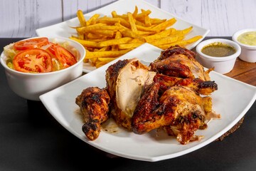 Deliciously charred and smoky Pollo a la Brasa (grilled chicken) served whole and in pieces, accompanied by crispy fries, fresh salad, and a flavorful dipping sauce. A classic Latin American dish, coo