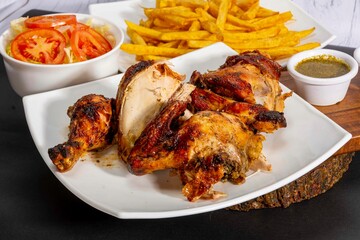 Deliciously charred and smoky Pollo a la Brasa (grilled chicken) served whole and in pieces, accompanied by crispy fries, fresh salad, and a flavorful dipping sauce. A classic Latin American dish, coo