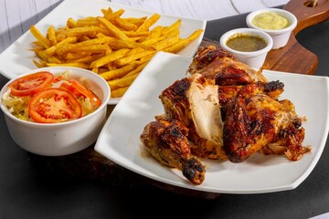 Deliciously charred and smoky Pollo a la Brasa (grilled chicken) served whole and in pieces,...