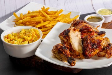 Deliciously charred and smoky Pollo a la Brasa (grilled chicken) served whole and in pieces, accompanied by crispy fries, fresh salad, and a flavorful dipping sauce. A classic Latin American dish, coo