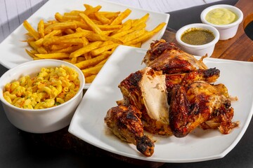 Deliciously charred and smoky Pollo a la Brasa (grilled chicken) served whole and in pieces, accompanied by crispy fries, fresh salad, and a flavorful dipping sauce. A classic Latin American dish, coo