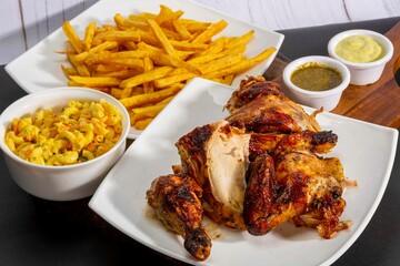 Deliciously charred and smoky Pollo a la Brasa (grilled chicken) served whole and in pieces, accompanied by crispy fries, fresh salad, and a flavorful dipping sauce. A classic Latin American dish, coo