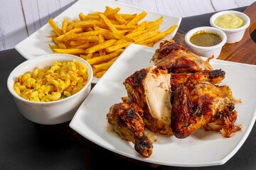 Deliciously charred and smoky Pollo a la Brasa (grilled chicken) served whole and in pieces, accompanied by crispy fries, fresh salad, and a flavorful dipping sauce. A classic Latin American dish, coo