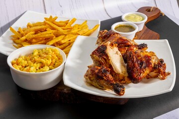 Deliciously charred and smoky Pollo a la Brasa (grilled chicken) served whole and in pieces, accompanied by crispy fries, fresh salad, and a flavorful dipping sauce. A classic Latin American dish, coo