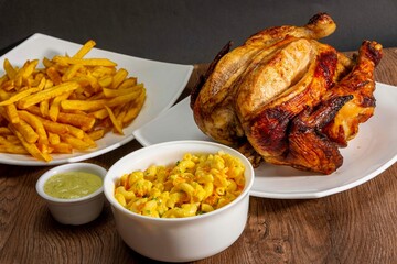 Deliciously charred and smoky Pollo a la Brasa (grilled chicken) served whole and in pieces, accompanied by crispy fries, fresh salad, and a flavorful dipping sauce. A classic Latin American dish, coo