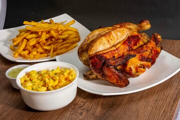 Deliciously charred and smoky Pollo a la Brasa (grilled chicken) served whole and in pieces, accompanied by crispy fries, fresh salad, and a flavorful dipping sauce. A classic Latin American dish, coo
