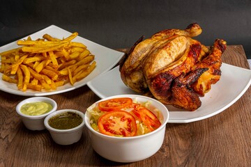 Deliciously charred and smoky Pollo a la Brasa (grilled chicken) served whole and in pieces, accompanied by crispy fries, fresh salad, and a flavorful dipping sauce. A classic Latin American dish, coo