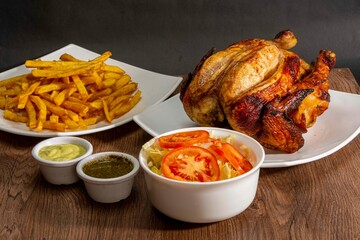 Deliciously charred and smoky Pollo a la Brasa (grilled chicken) served whole and in pieces, accompanied by crispy fries, fresh salad, and a flavorful dipping sauce. A classic Latin American dish, coo