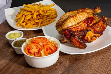 Deliciously charred and smoky Pollo a la Brasa (grilled chicken) served whole and in pieces, accompanied by crispy fries, fresh salad, and a flavorful dipping sauce. A classic Latin American dish, coo
