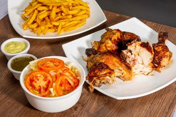 Deliciously charred and smoky Pollo a la Brasa (grilled chicken) served whole and in pieces, accompanied by crispy fries, fresh salad, and a flavorful dipping sauce. A classic Latin American dish, coo