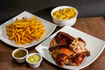 Deliciously charred and smoky Pollo a la Brasa (grilled chicken) served whole and in pieces, accompanied by crispy fries, fresh salad, and a flavorful dipping sauce. A classic Latin American dish, coo