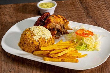 Deliciously charred and smoky Pollo a la Brasa (grilled chicken) served whole and in pieces, accompanied by crispy fries, fresh salad, and a flavorful dipping sauce. A classic Latin American dish, coo