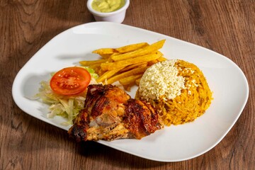 Deliciously charred and smoky Pollo a la Brasa (grilled chicken) served whole and in pieces, accompanied by crispy fries, fresh salad, and a flavorful dipping sauce. A classic Latin American dish, coo
