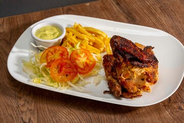 Deliciously charred and smoky Pollo a la Brasa (grilled chicken) served whole and in pieces, accompanied by crispy fries, fresh salad, and a flavorful dipping sauce. A classic Latin American dish, coo