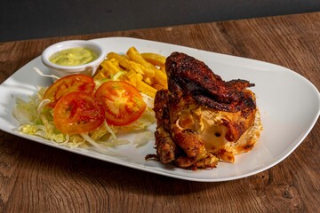 Deliciously charred and smoky Pollo a la Brasa (grilled chicken) served whole and in pieces, accompanied by crispy fries, fresh salad, and a flavorful dipping sauce. A classic Latin American dish, coo
