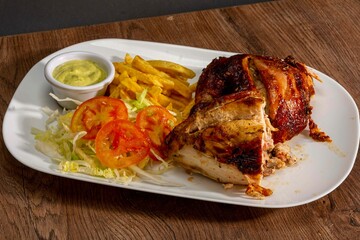 Deliciously charred and smoky Pollo a la Brasa (grilled chicken) served whole and in pieces, accompanied by crispy fries, fresh salad, and a flavorful dipping sauce. A classic Latin American dish, coo