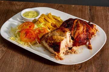 Deliciously charred and smoky Pollo a la Brasa (grilled chicken) served whole and in pieces, accompanied by crispy fries, fresh salad, and a flavorful dipping sauce. A classic Latin American dish, coo