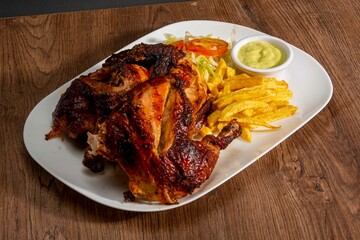 Deliciously charred and smoky Pollo a la Brasa (grilled chicken) served whole and in pieces, accompanied by crispy fries, fresh salad, and a flavorful dipping sauce. A classic Latin American dish, coo