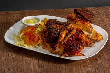 Deliciously charred and smoky Pollo a la Brasa (grilled chicken) served whole and in pieces, accompanied by crispy fries, fresh salad, and a flavorful dipping sauce. A classic Latin American dish, coo