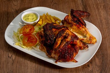 Deliciously charred and smoky Pollo a la Brasa (grilled chicken) served whole and in pieces, accompanied by crispy fries, fresh salad, and a flavorful dipping sauce. A classic Latin American dish, coo