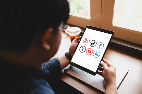 Bangkok. Thailand. SEPTEMBER 13,2024 : A woman types on a lablet displaying icons of popular social media platforms, including Instagram, TikTok, Facebook, LinkedIn, YouTube, and X.